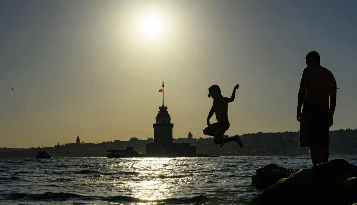 A child jumps into the sea in front of the Maiden?s Tower in Istanbul on June 28, 2026. Europe's deadly heatwave pushed east with hundreds of millions still sweltering across the continent despite fleeting relief from overnight storms, notably in France and Belgium. (Photo by Yasin AKGUL/AFP)