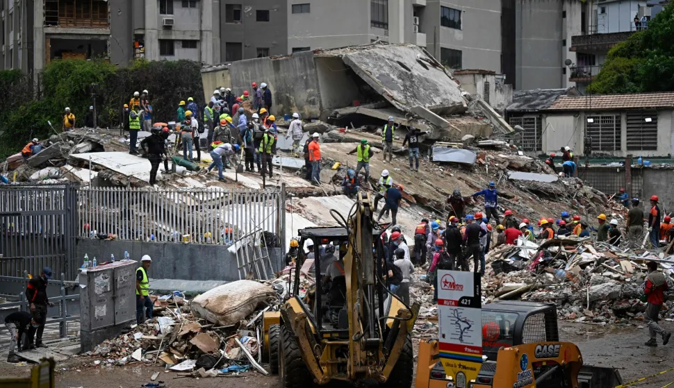 Workers remove debris from a collapsed building in the San Bernardino neighborhood of Caracas on June 28, 2026, following earthquakes. Thousands of rescuers, relatives and volunteers dig day and night through mounds of concrete to find survivors of the earthquakes that struck Venezuela more than three days ago, leaving nearly 1,500 dead and tens of thousands missing. (Photo by Federico PARRA/AFP)