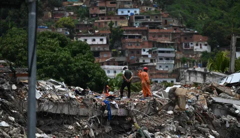 A rescue worker raises his hand to silence people to try to find survivors at a collapsed building following the June 24 twin earthquakes, in Caraballeda, La Guaira state, Venezuela, on June 30, 2026,. Tens of thousands of people urgently need food and shelter in Venezuela due to the devastation from two huge earthquakes that killed more than 1,700 and injured 5,000, the UN said on June 30, 2026, as doctors warned of potential outbreaks of disease. (Photo by Juan BARRETO/AFP)
