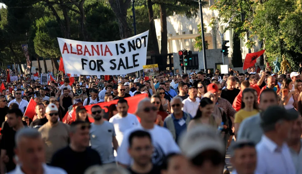 Protestors hold banners as they gather in front of the Albanian Prime Minister's Office to demonstrate against the construction on the southern coast of Albania a luxury resort near a protected natural area, in Tirana, on June 10, 2026. Several thousand citizens have demonstrated in Tirana for more than a week to demand transparency around a tourist complex project allegedly linked to US President's son-in-law, Jared Kushner. The demonstrators argue that the estimated $1.2 billion project, led by Kushner and his wife Ivanka, will harm the environment, with plans for luxury hotels in the protected area of Vjosa-Narta on the southern coast. (Photo by Adnan Beci/AFP)