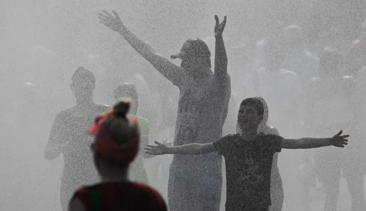 Police use water cannon to spray people with water as the arrive at the Olympic stadium for a concert of US singer Bruno Mars on June 28, 2026, in Berlin, as the German capital is expected to reach temperatures around 40 degrees Celsius during a heatwave in Europe. Tens of millions are braving a weekend of extreme temperatures in Europe as a deadly heatwave moves eastwards, with some countries announcing rising death tolls and health services warning of saturation. While some mild relief is expected Sunday in western Europe, German forecasters are warning that more temperature records could still be broken over the weekend as eastern countries issue a slew of red alerts for the coming days. (Photo by RALF HIRSCHBERGER/AFP)