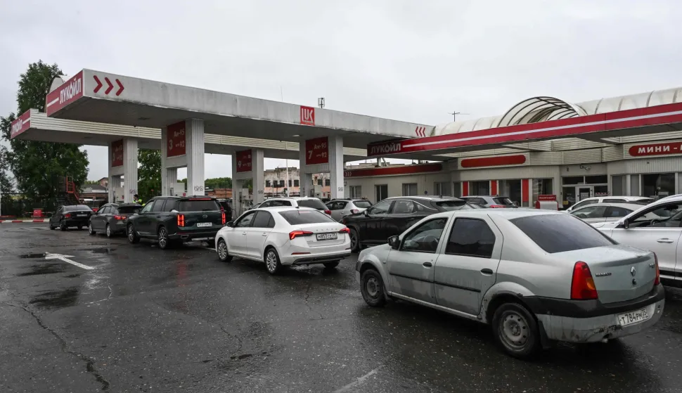 People queue to refuel their cars at a Lukoil petrol station in Vologda on July 14, 2026. Russia -- one of the world's largest oil producers -- has introduced a swath of restrictions on petrol sales across the country, as Ukrainian strikes on its refineries, depots and logistics crimp domestic supply. Several regions have introduced rationing, while some gas stations and chains have sold out or closed due to a lack of supplies. (Photo by Igor IVANKO/AFP)