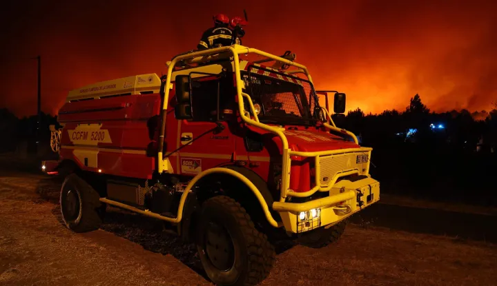 This photograph shows a firefighters' vehicle Camion Citerne Feux de Foret Moyen - CCFM 5200 (Medium-sized Forest Fire Tanker) during a wildfire in Le Porge, south-western France on July 22, 2026. A fast-moving wildfire has burned 900 hectares north of Arcachon Bay in southwestern France, forcing the evacuation of more than 4,000 residents and tourists. The blaze, described by firefighters as exceptionally intense, spread sixfold in less than three hours through dense pine forests and is now advancing toward Ares and Lege-Cap-Ferret. The area was previously devastated by major wildfires in 2022. (Photo by ROMAIN PERROCHEAU/AFP)