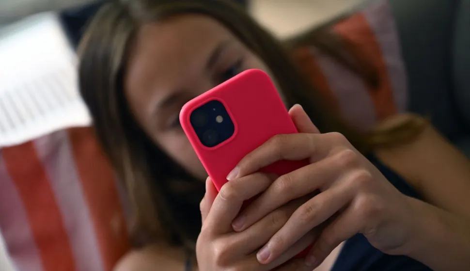 A teenager looks at her smartphone in Brussels on July 7, 2026. The European Commission estimated, on July 6, 2026, that the French bill banning social media access for children under 15 was not fully compatible with European Union law, while reaffirming its support for the initiative. Like France, Spain and Denmark are also working on the introduction of a digital age of majority to follow Australia's example, who became in December 2025 the first country to implement such a law. (Photo by Nicolas TUCAT/AFP)