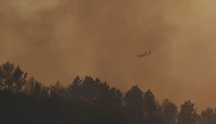 A Dash firefighting aircraft is seen through smoke as it flies over a wildfire in Correns, southeastern France, on August 1, 2026. The situation on the fire front remained ?extremely precarious? in the evening on August 1 evening in the southeastern Var department, due to a heatwave and strong winds, whilst in the Gironde most of those who had been evacuated were able to return to their homes after ten days of battling a mega-fire that is now ?contained? but not ?extinguished?. (Photo by CLEMENT MAHOUDEAU/AFP)