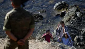 A member of the Spanish Army's 'Regulares' infantry forces watches a group of migrants near the border post of the Spanish enclave of Ceuta on August 2, 2026. At least 72 people died during last week's mass influx of migrants into Spain's Ceuta enclave, when tens of thousands of people mostly swam around the border post from Morocco, local officials said today. Most of the estimated 60,000 people who rushed into Spain's north African territory have returned to Morocco since the territory's largest mass migrant crossing. (Photo by Henry NICHOLLS/AFP)
