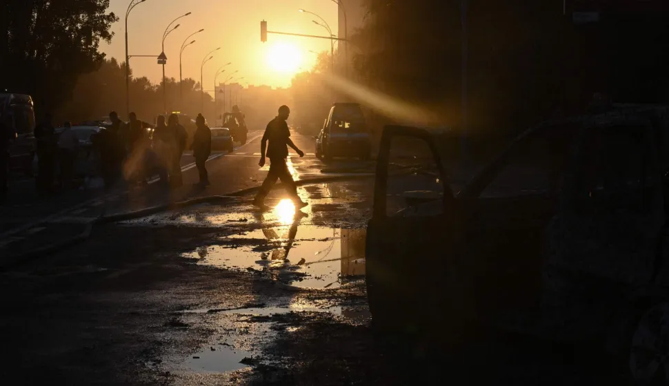 EDITORS NOTE: Graphic content/A person crosses the street past a damaged car and debris on the road following a Russian ballistic missile strike in the Ukrainian capital of Kyiv on August 1, 2026, amid the Russian invasion in Ukraine. Russian attacks on Ukraine's capital killed at least nine people and wounded more than two dozen others, local officials said on August 1, 2026, with strikes damaging homes and causing fires across the city. As Moscow has increased its long-range strikes on Ukrainian towns and cities, Kiev has pressed its allies for air defence support. The United Nations found June 2026 was the deadliest month for civilians in Ukraine since April 2022. (Photo by Genya SAVILOV/AFP)