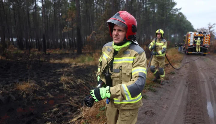 Ukrainian firefighters aiding in the fight against France's ongoing wildfires work to put out smouldering vegetation near the village of Le Temple, southwestern France, on August 3, 2026. A massive fire in the near the Arcachon Bay in the Gironde department started on July 22, forcing 220 people to flee their homes to safety. The fire went on to incinerate some 42,000 hectares (104,000 acres) of pine forest along the Atlantic coastline, destroying some 240 homes in its wake. (Photo by ROMAIN PERROCHEAU/AFP)