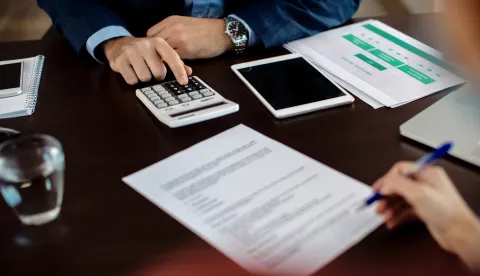 Close-up of insurance agent calculating costs an agreement while having a meeting with a client.Građani su nenamjenske kredite podizali uz stambene, &raquo;krpali&laquo; su njima kućni budžet, ali i kretali u investicije, banka kredit dug novac ilustracija magnific