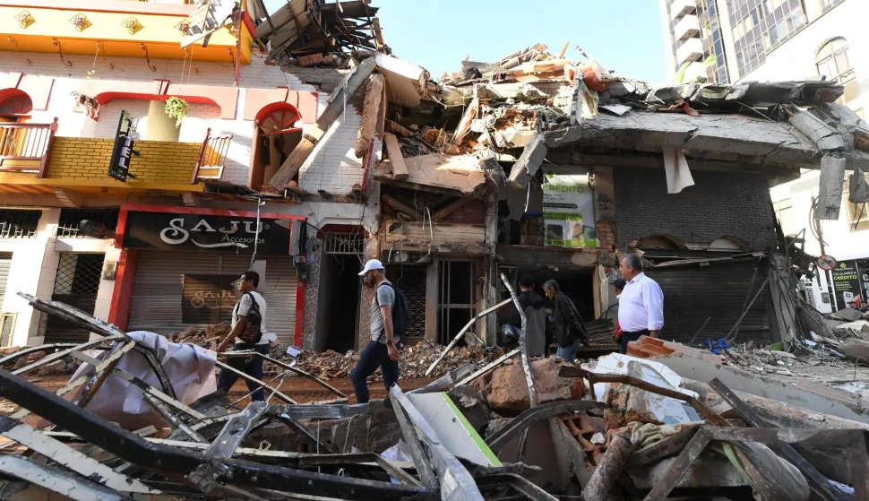 People walk past the rubble of a collapsed building after an earthquake in Pereira, Colombia on August 11, 2026. (Photo by Jaime SALDARRIAGA/AFP)