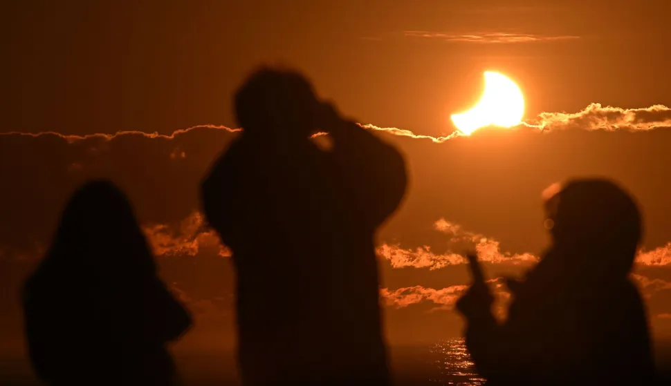 (FILES) People watch a partial solar eclipse?at New Brighton, a coastal suburb of Christchurch, on September 22, 2025. Day will briefly turn into night across a swathe of northern Spain on August 12, when the Moon will completely cover the Sun during a rare total solar eclipse.Here is what you need to know about the total eclipse, which is the first visible in mainland Europe since 2006. (Photo by Sanka Vidanagama/AFP)