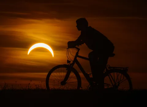 12 August 2026, Brandenburg, Jacobsdorf: A boy on a bicycle watches the partial solar eclipse in eastern Brandenburg. According to the German Weather Service, when the partial solar eclipse is visible over Germany this evening, weather conditions will be ideal for viewing it almost everywhere at that time. Photo: Patrick Pleul/dpa Photo: Patrick Pleul/DPA