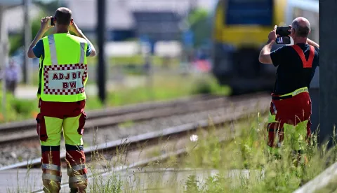 Emergency services take images with their smartphones at the site of an accident after a train crashed into a school bus, at the railway crossing Vierhuizen in Buggenhout on May 26, 2026. (Photo by DIRK WAEM/BELGA/AFP)/Belgium OUT