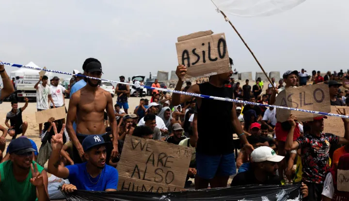 Migrants hold signs reading "Asilo," Spanish for "asylum," as they gather in Ceuta, Spain, August 16, 2026. REUTERS/Maria Alejandra Cardona Photo: MARIA ALEJANDRA CARDONA/REUTERS