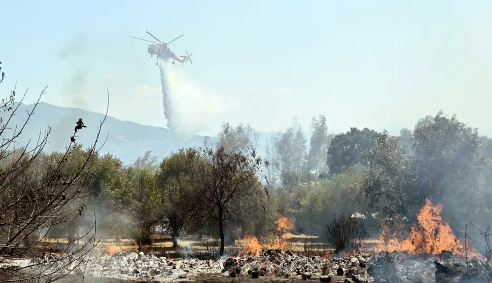 epa11468679 A firefighting helicopter drops water during a wildfire in Patra region, on Peloponnese, Greece, 09 July 2024. Powerful firefighting forces are operating in the area of ​​Gerokomeio, Patras, in order to bring under control the fire which is burning low vegetation and is located near houses. Also, the assistance of aerial firefighting means has been requested, while the Police is on standby, so that, if necessary, residents of the area can be evacuated as a precaution. More than 30 firefighters with a walking department team and 10 vehicles, as well as three aerial vehicles are operating in the area. EPA/GIOTA LOTSARI