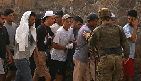 A Spanish soldier controls a group of migrants on their way back towards the Moroccan border, following their illegal crossing into the Spanish enclave of Ceuta, on August 1, 2026. Almost all of the thousands of migrants who entered Spain's enclave of Ceuta in North Africa had left today, officials said, as the European countries bolstered their border controls. Some 60,000 migrants entered Ceuta over just a few days from neighbouring Morocco, the enclave's regional president told reporters, but yesterday evening officials said more than 48,000 had already returned. (Photo by JORGE GUERRERO/AFP)