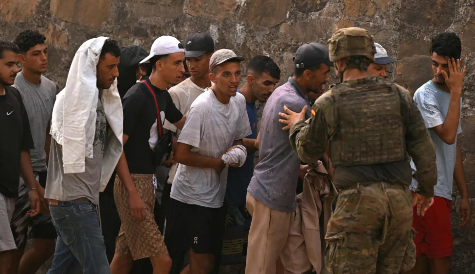 A Spanish soldier controls a group of migrants on their way back towards the Moroccan border, following their illegal crossing into the Spanish enclave of Ceuta, on August 1, 2026. Almost all of the thousands of migrants who entered Spain's enclave of Ceuta in North Africa had left today, officials said, as the European countries bolstered their border controls. Some 60,000 migrants entered Ceuta over just a few days from neighbouring Morocco, the enclave's regional president told reporters, but yesterday evening officials said more than 48,000 had already returned. (Photo by JORGE GUERRERO/AFP)