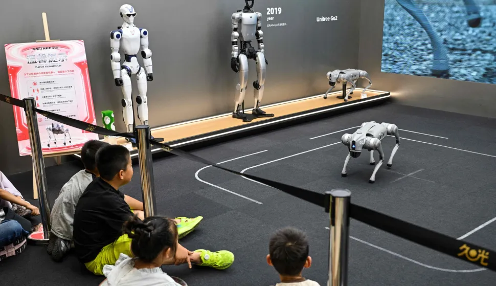 Children look at a remote-controlled robot by Unitree Robotics while visiting the Unitree Robotics Embodied Intelligence Experience Center in the Jing' an district in Shanghai on August 17, 2026. (Photo by Hector RETAMAL/AFP)