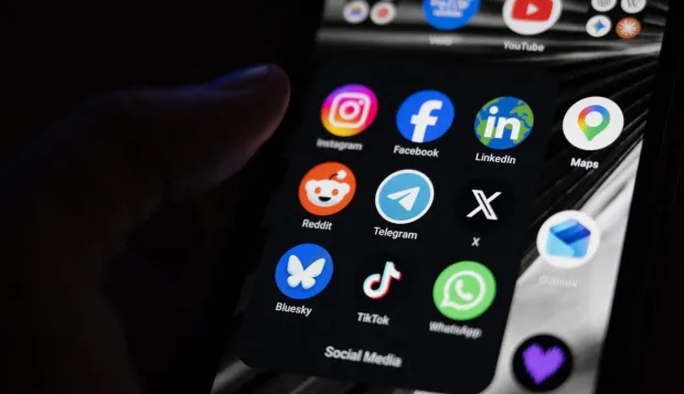 (FILES) This photograph shows a set up smart-phone screen displaying the logo of main social media platforms including Instagram, Facebook, LinkedIn, Reddit, Telegram, X, Bluesky, Tiktok and Whatsapp in Saint-Mande, east of Paris, on April 29, 2026. On August 14, 2026, the French Constitutional Council struck down the ban on social media for under-15s, ruling that this measure constitutes "a disproportionate infringement" of their freedom of expression. (Photo by Martin LELIEVRE/AFP)