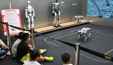 Children look at a remote-controlled robot by Unitree Robotics while visiting the Unitree Robotics Embodied Intelligence Experience Center in the Jing' an district in Shanghai on August 17, 2026. (Photo by Hector RETAMAL/AFP)