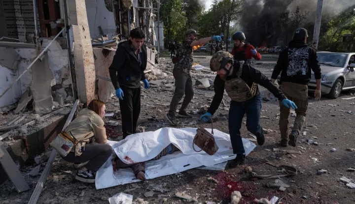 EDITORS NOTE: Graphic content/This handout photograph taken and released on May 5, 2026 by the press service of the 93rd Kholodnyi Yar Separate Mechanized Brigade of the Ukrainian Ground Forces shows people gathered next to a victim of a Russian air attack wrapped in a plastic sheet in Kramatorsk, eastern Donetsk region, amid the Russian invasion of Ukraine. Russian attacks killed 21 people in cities across Ukraine on May 5, 2026, as President Volodymyr Zelensky condemned Moscow's "utter cynicism" for launching deadly strikes while seeking a truce to stage its May 9 patriotic parade. The attacks, hitting the cities of Zaporizhzhia, Kramatorsk and Dnipro, came hours before a Ukrainian-suggested ceasefire. (Photo by IRYNA RYBAKOVA/The 93rd Kholodnyi Yar Separate/AFP)/RESTRICTED TO EDITORIAL USE - MANDATORY CREDIT "AFP PHOTO/IRYNA RYBAKOVA/PRESS SERVICE OF THE 93RD KHOLODNYI YAR SEPARATE MECHANIZED BRIGADE" - NO MARKETING NO ADVERTISING CAMPAIGNS - DISTRIBUTED AS A SERVICE TO CLIENTS