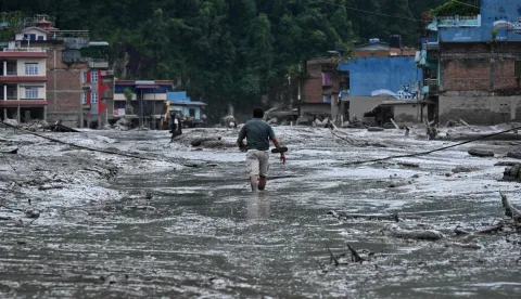 A resident walks along a street covered in mud following flash floods and a landslide disaster in Devghat, in Nepal's Nuwakot district on August 26, 2026. A massive flood and landslide disaster on the Nepal-Tibet border killed at least 103 people on August 26, 2026 and left several hundred missing, many of them foreign tourists. Aid workers said entire settlements had been "wiped out". Some 403 tourists -- 341 of them foreigners -- were unaccounted for several hours after the disaster struck, according to the tourism ministry. (Photo by PRAKASH MATHEMA/AFP)