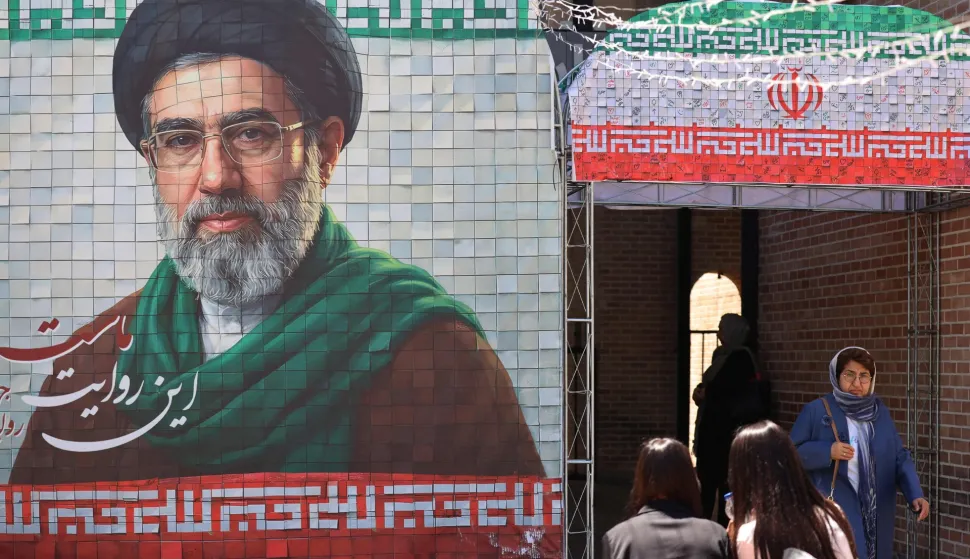 A commuter walks past a large tiled image of Iran's current leader Ayatollah Mojtaba Khamenei, at the entrance to the metro in Tehran on May 9, 2026. (Photo by ATTA KENARE/AFP)/