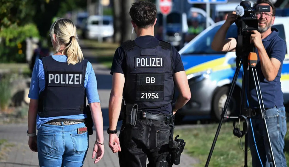 Police officers walk near the scene at a school in Gosen-Neu Zittau, south-east of Berlin on August 27, 2026, after two people were killed in a "violent incident" at the school. Local media reported August 27 that an 18-year-old female student and a 30-year-old man had died. Regional public broadcaster RBB and a local daily said that an alarm had been triggered at a secondary school in the town of Gosen-Neu Zittau, with police confirming they were on the scene and that a suspect had been arrested. (Photo by RALF HIRSCHBERGER/AFP)