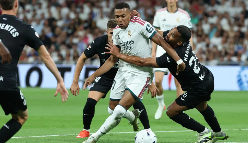 Real Madrid's French forward #10 Kylian Mbappe (C) vies for the ball with Real Sociedad's Venezuelan midfielder #21 Yangel Herrera during the Spanish league football match between Real Madrid CF and Real Sociedad at Santiago Bernabeu Stadium in Madrid on August 26, 2026. (Photo by Thomas COEX/AFP)