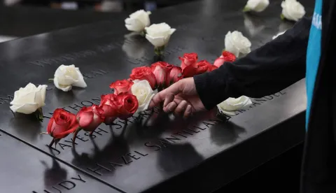 A man touches flowers at the memorial during the 25th anniversary commemoration of the September 11, 2001 attacks at the National September 11 Memorial in New York on September 11, 2026. (Photo by Spencer Platt/POOL/AFP)