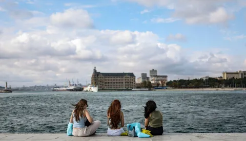 People enjoy the shore of Kadikoy district as Haydarpasa Train station is seen in the background in Istanbul, on September 13, 2026. (Photo by BERK OZKAN/AFP)