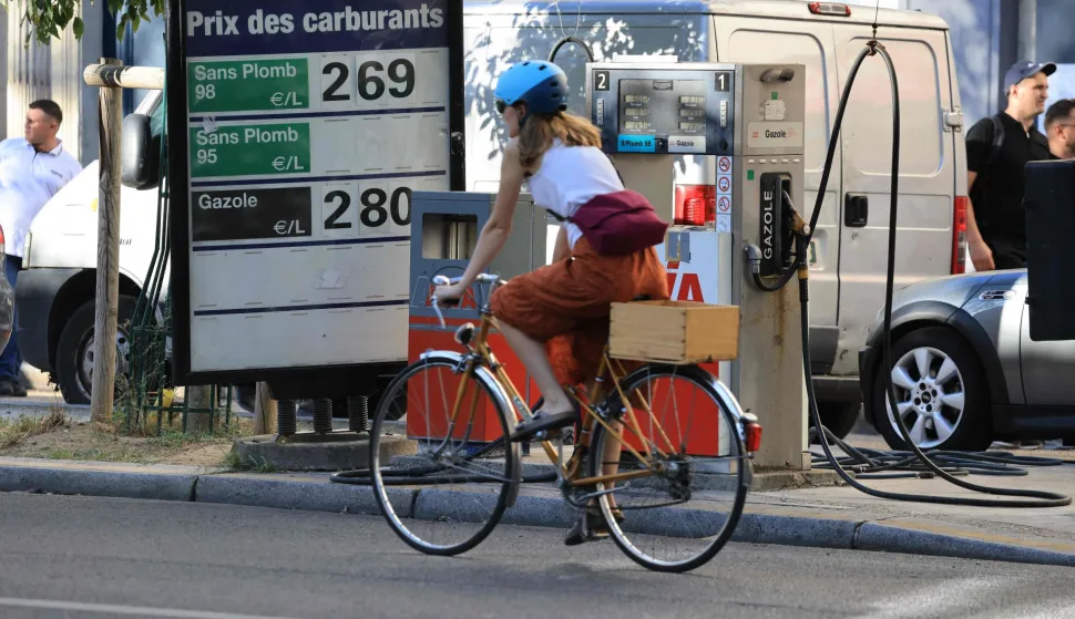 A cyclist rides her bicycle past a board indicating fuel prices at a petrol station in Paris on September 14, 2026. (Photo by Ludovic MARIN/AFP)