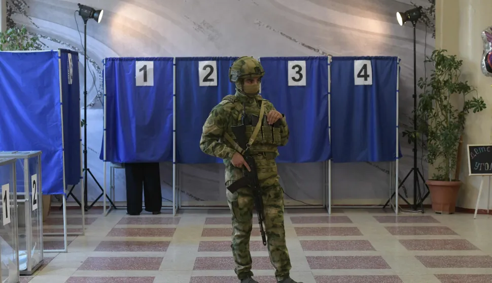 People vote in Russia's parliamentary election as a Russian serviceman secures a polling station in Donetsk, Russian-controlled Ukraine, on September 18, 2026, amid the ongoing Russian-Ukrainian conflict. (Photo by AFP)