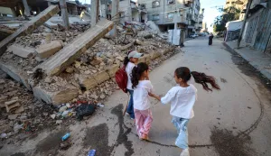TOPSHOT - Palestinian children walk to school past the rubble of a destroyed building as the academic year begins in Bureij in the central Gaza Strip on September 19, 2026. (Photo by Eyad Baba/AFP)