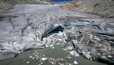 (FILES) This photograph shows a group of hikers making their way past a melt hole on the melting Rh?ne Glacier, above Gletsch in the Swiss Alps, on July 24, 2026. Swiss glaciers have lost nearly 20% of their volume over the past five years, including 5.5% this year, following a record-hot summer and low winter snowfall, according to data from the Swiss Glacier Monitoring Network (Glamos) published on October 1, 2026. (Photo by Fabrice COFFRINI/AFP)