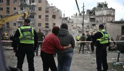 TOPSHOT - Local residents hug as they look at a multi-floor residential building destroyed following a Russian aerial strike in Pryluky on October 7, 2026, amid the Russian invasion of Ukraine. In Pryluky, the death toll has risen to nine people, including three children, and 40 people are known to have been injured, including seven children, the Emergency Service said on October 7, 2026. (Photo by Genya Savilov/AFP)