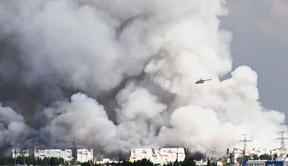 A helicopter flies past smoke rising from a warehouse for a Russian e-commerce giant near Saint Petersburg after being hit by Ukrainian drones early on July 24, 2026 morning, triggering a fire that sent smoke pouring over the historic city, according to local officials. At least 17 people were killed on July 24, 2026 in Russian and Ukrainian long-range strikes -- including just outside Kyiv and hundreds of miles east of Moscow -- as both sides intensify strikes with diplomacy in a deadlock. Ukraine also attacked warehouses belonging to Russian online retail giant Wildberries outside Saint Petersburg -- targeting Russia's equivalent of Amazon for the third time this week. (Photo by AFP)