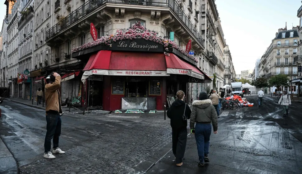 Pedestrians react as they walk past the burnt down restaurant "La Barrique" near Place de la Republique, central Paris, on October 18, 2026 a day after nationwide protests against the "high cost of living". France's Prime Minister Sebastien Lecornu said 1,200 people were arrested in protests across the country on October 17, and 150 police were hurt as Clashes between police and protesters, massive looting and multiple blazes gripped France as nationwide marches against soaring inflation degenerated into street violence of "extreme intensity". (Photo by Matthieu RONDEL/AFP)