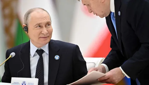 In this pool photograph distributed by the Russian state agency Sputnik, Russia's President Vladimir Putin interacts with Kremlin foreign policy aide Yuri Ushakov during a meeting of the Commonwealth of Independent States (CIS) Heads of State Council in Turkmenbashi on October 9, 2026. (Photo by Sergei BOBYLYOV/POOL/AFP)