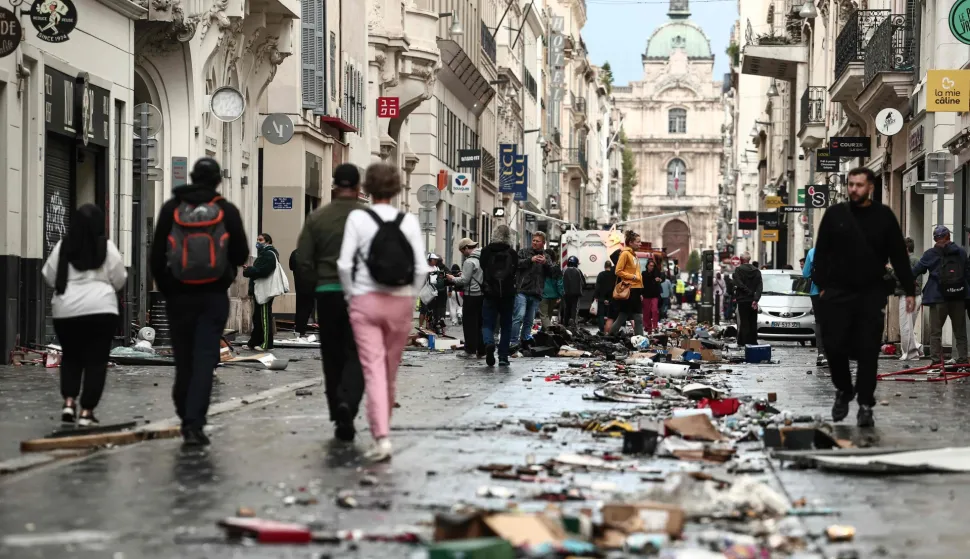 TOPSHOT - Pedestrians walk along a street covered in debris a day after nationwide protests against the "high cost of living", in Marseille on October 18, 2026. France's Prime Minister said 1,200 people were arrested in protests across the country on October 17, and 150 police were hurt during clashes between police and protesters. Massive looting and multiple blazes gripped France as nationwide marches against soaring inflation degenerated into street violence of "extreme intensity". (Photo by Thibaud MORITZ/AFP)