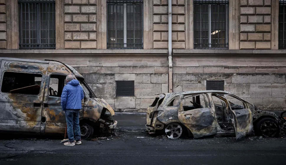 A local resident looks inside a burnt out van on Rue Yves Toudic destroyed after a weekend of protests against the "high cost of living", in central Paris on October 19, 2026. France's Prime Minister said 1,200 people were arrested in protests across the country on October 17, and 150 police were hurt during clashes between police and protesters. Massive looting and multiple blazes gripped France as nationwide marches against soaring inflation degenerated into street violence of "extreme intensity". (Photo by Kiran RIDLEY/AFP)