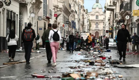 TOPSHOT - Pedestrians walk along a street covered in debris a day after nationwide protests against the "high cost of living", in Marseille on October 18, 2026. France's Prime Minister said 1,200 people were arrested in protests across the country on October 17, and 150 police were hurt during clashes between police and protesters. Massive looting and multiple blazes gripped France as nationwide marches against soaring inflation degenerated into street violence of "extreme intensity". (Photo by Thibaud MORITZ/AFP)