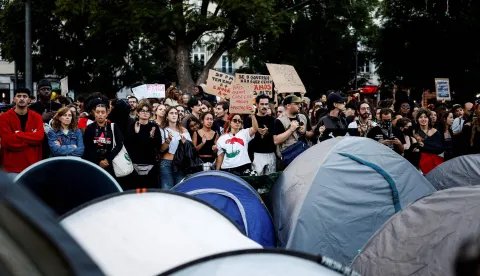 Demonstrators stand next to tents set up to protest against housing shortage, soaring rents and low wages in central Lisbon on October 17, 2026. Thousands of people marched on October 17, 2026 through the centre of Lisbon at the call of the CGTP trade union to protest against increasingly difficult living conditions. The slogans and demands focus mainly on higher wages and pensions, as well as protests against the rising cost of housing and fuel. (Photo by Filipe AMORIM/AFP)