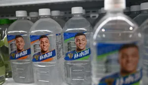 Bottles of Dongpeng Beverage Group's "Bushuila" electrolyte drink featuring French football star Kylian Mbappe on the packaging are displayed at a convenience store in Beijing on October 27, 2026. Kylian Mbappe was dropped October 27 by two major brands in China after a video circulated online in which the French football star apparently joked about former leader Mao Zedong. (Photo by Pedro PARDO/AFP)
