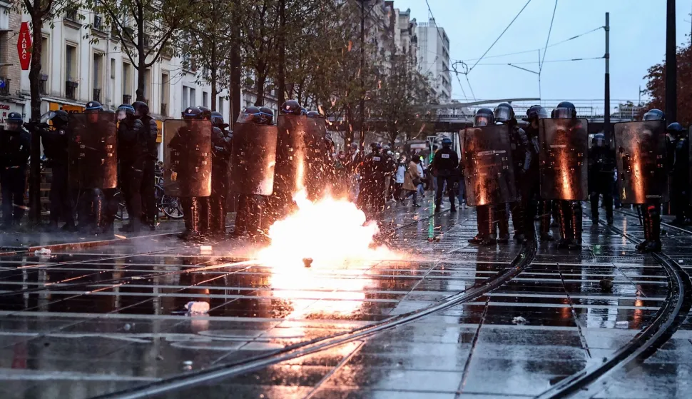 TOPSHOT - French Police officers in riot gear (L) and French Gendarmes stand guard as tear gas cansiter explodes during a demonstration in favor of purchasing power, the protection of public services, and fiscal and social justice, in Paris on October 24, 2026 as part of a nationwide call for mobilisation bringing together former members of the Yellow Vest movement, labor unions, high school and university students. Protests by high school students over learning conditions sparked a movement that has since spread nationwide, fuelled by broader anger over the rising cost of living. About 70,000 security personnel will be deployed on October 24, 2026, Interior Minister said at a news conference, warning that calls for violence and looting were circulating on social media. (Photo by Sameer AL-DOUMY/AFP)